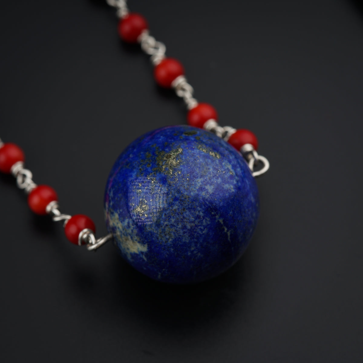 a necklace with a blue ball and red beads