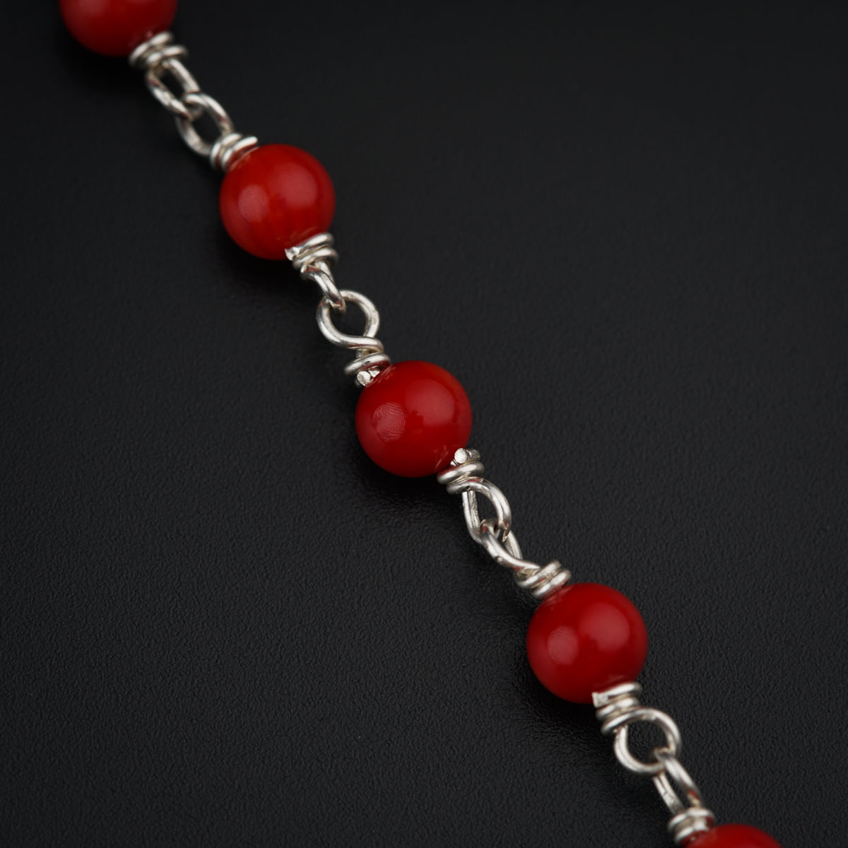 a close up of a red beaded bracelet on a black surface