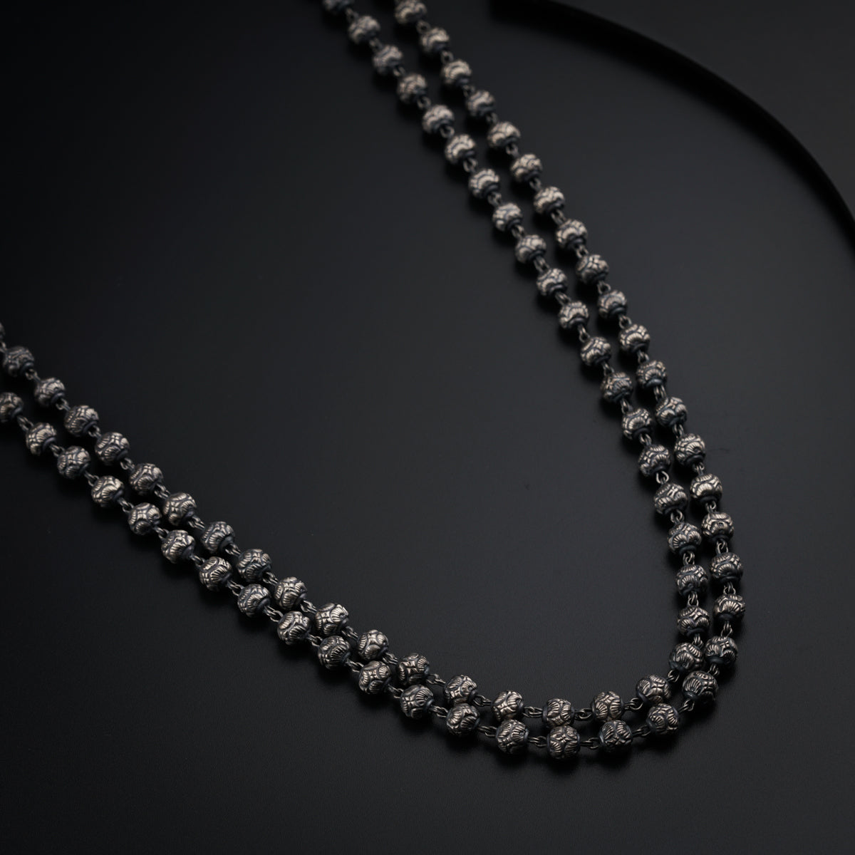 a black beaded necklace on a black surface