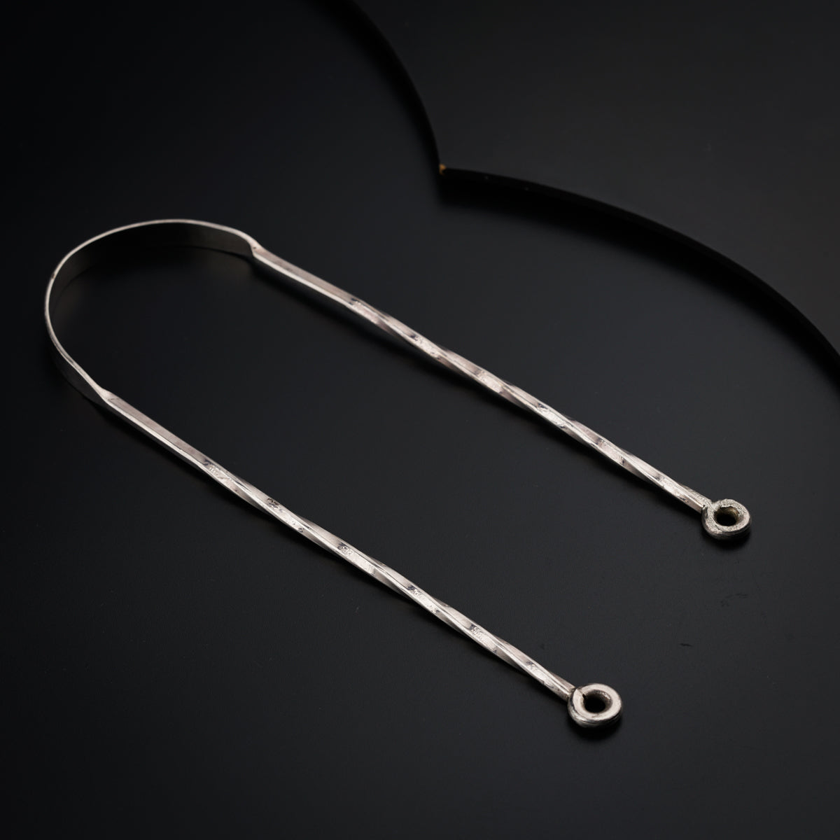 a pair of metal hair clips on a black surface