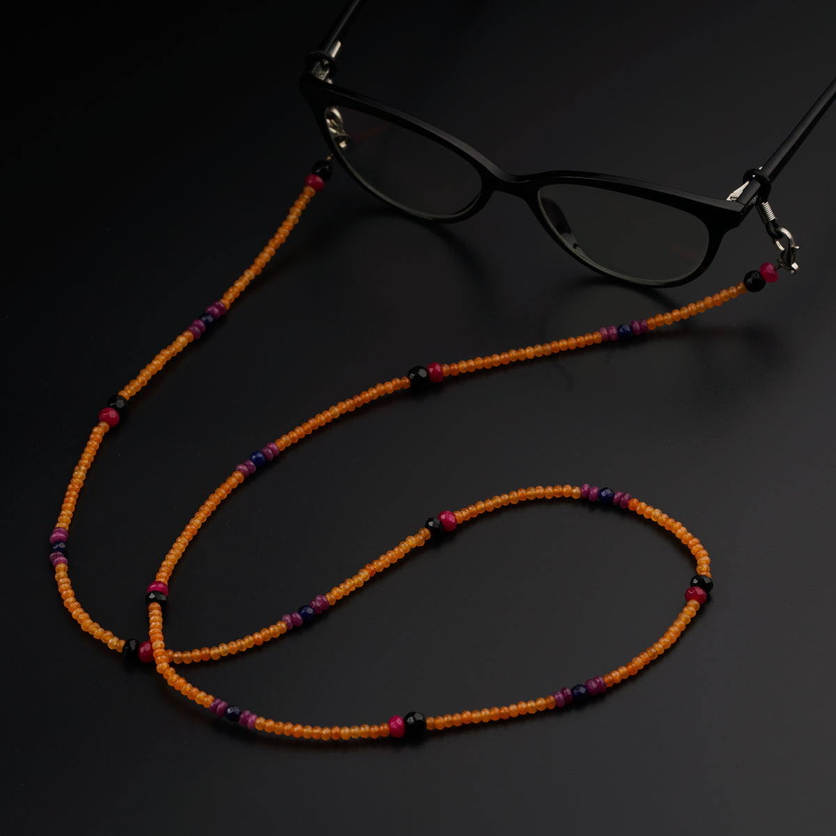 a pair of glasses sitting on top of a beaded necklace