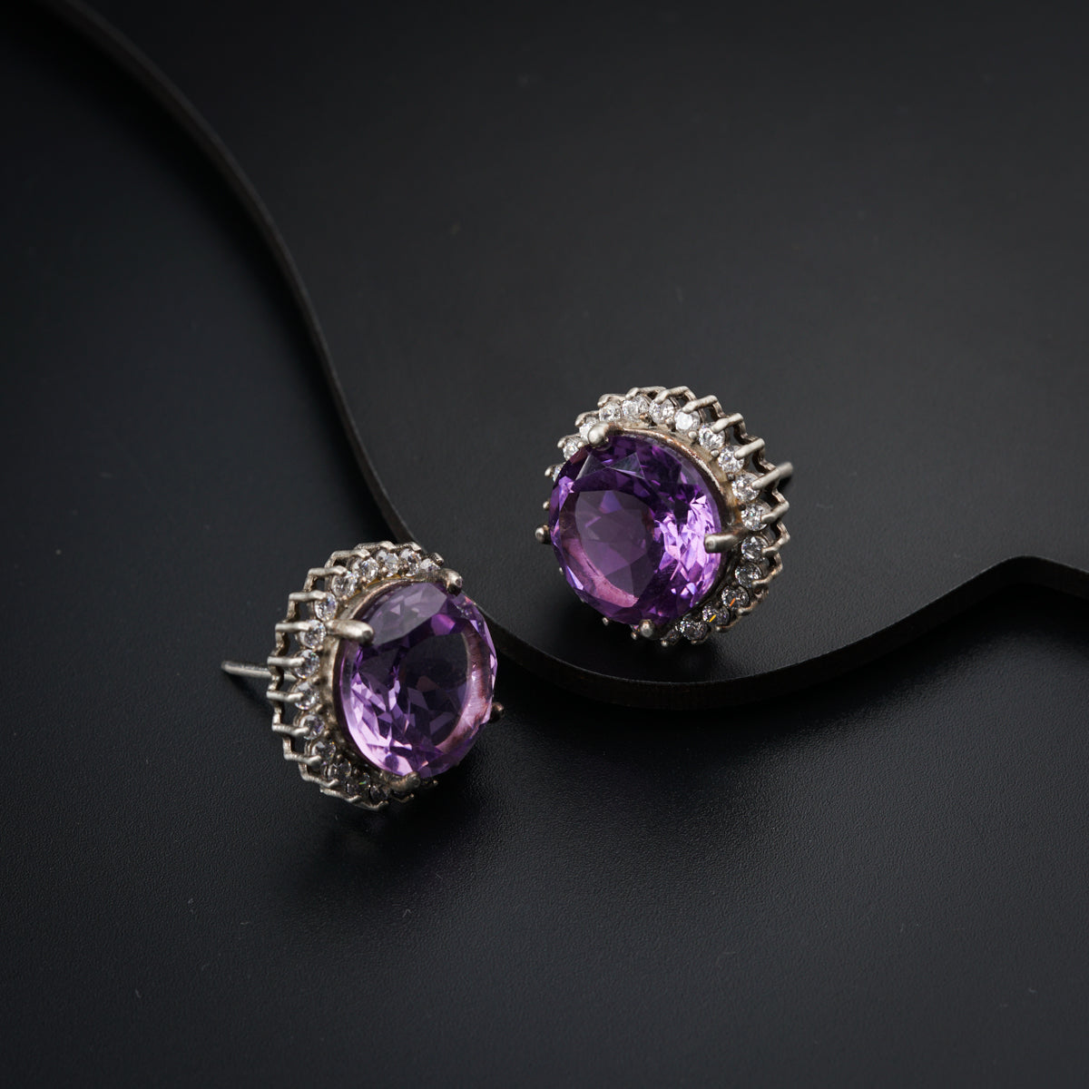 a pair of earrings with amethyst colored stones