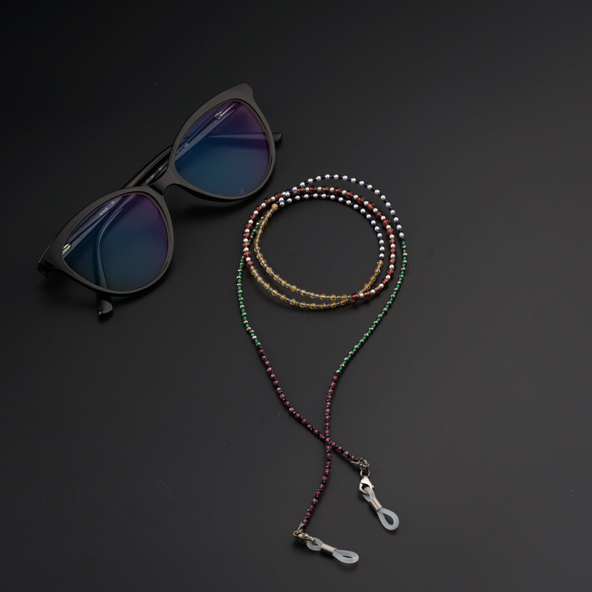 a pair of sunglasses and a beaded lanyard on a black surface