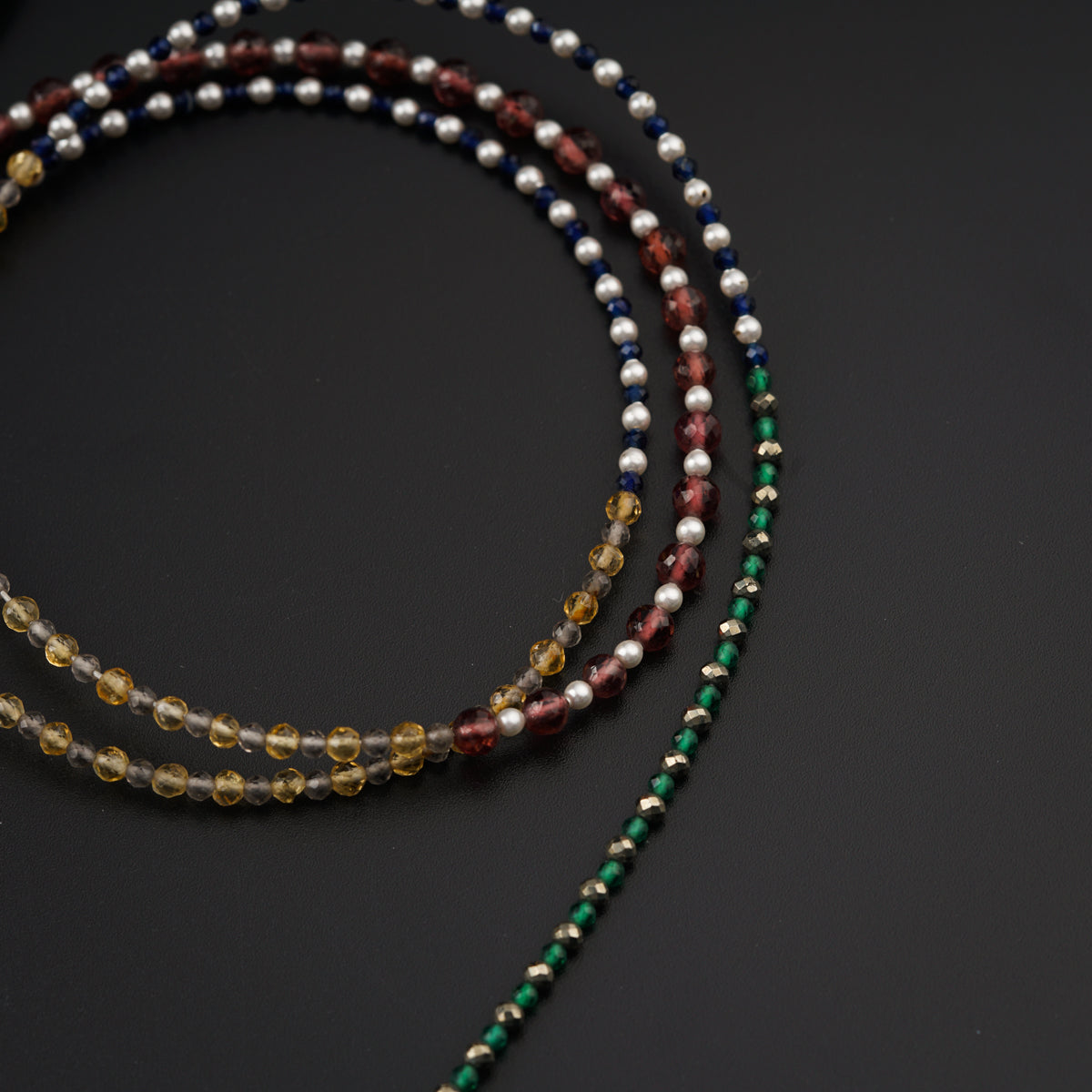 a long necklace with multicolored beads on a black surface
