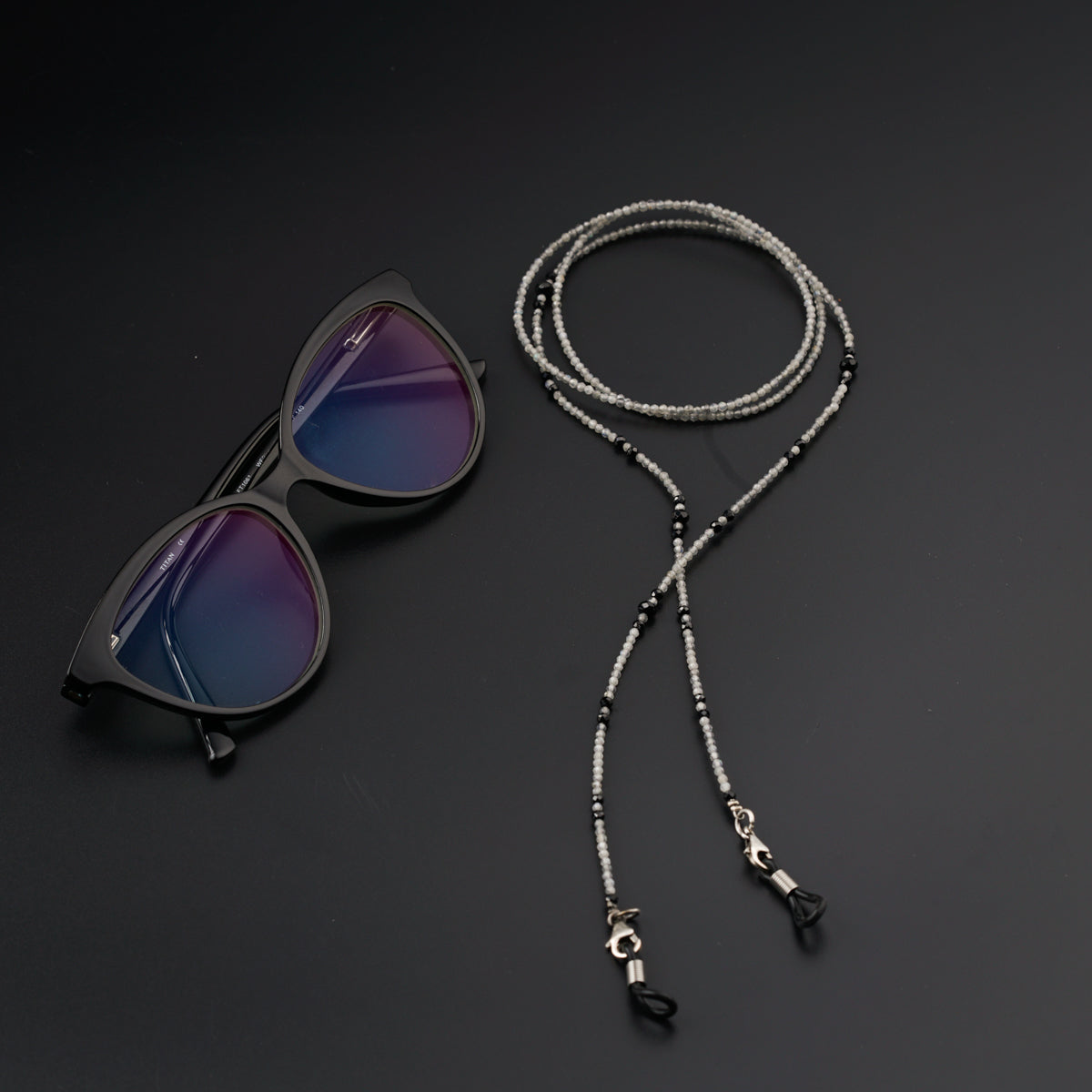 a pair of sunglasses and a lanyard on a black surface