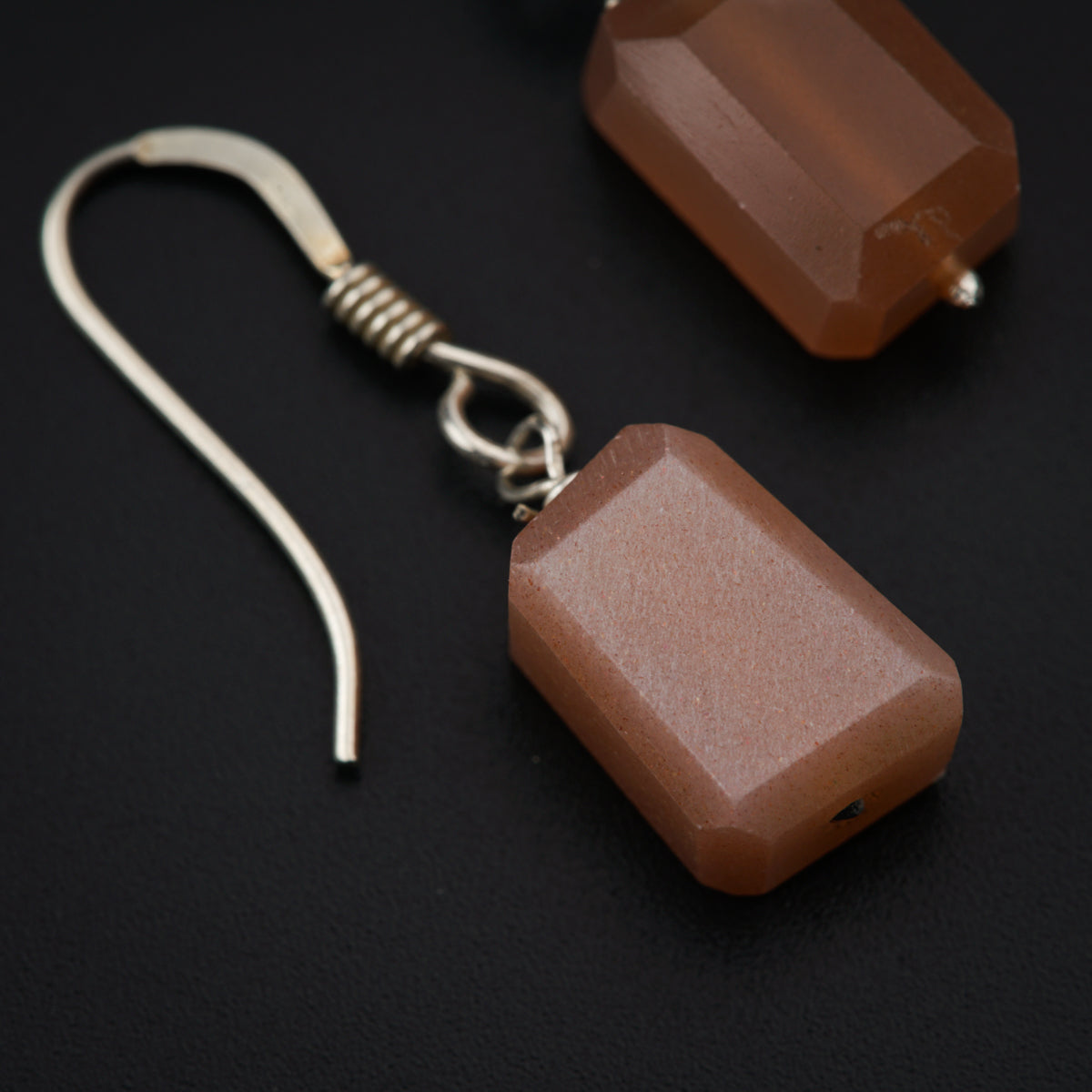 a pair of earrings with brown beads on a black background