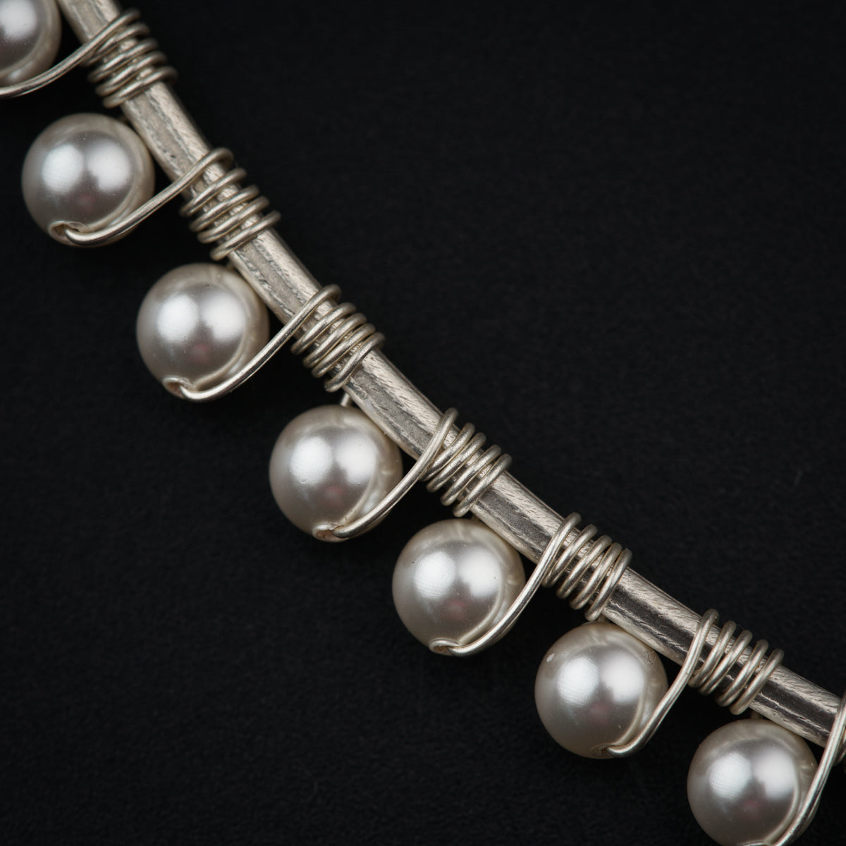 a close up of a necklace with pearls on it