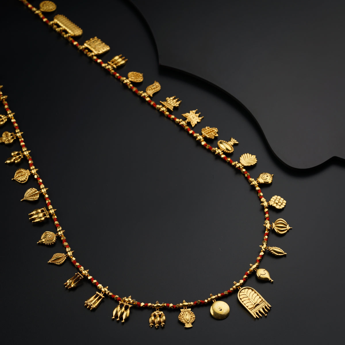 a gold necklace with red beads and gold charms