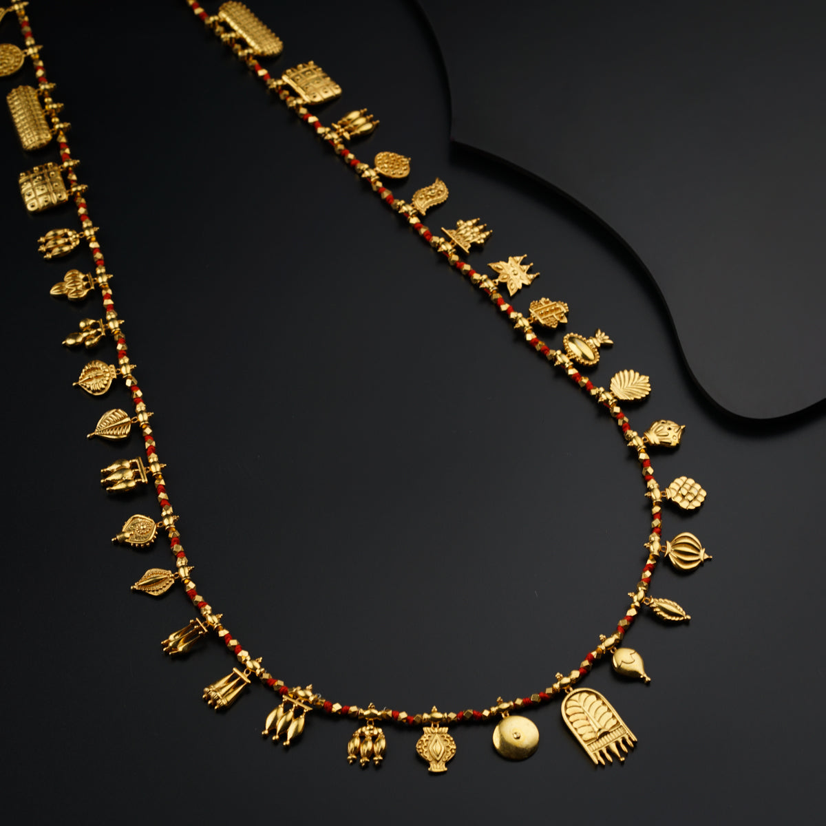 a gold necklace with red beads and gold charms
