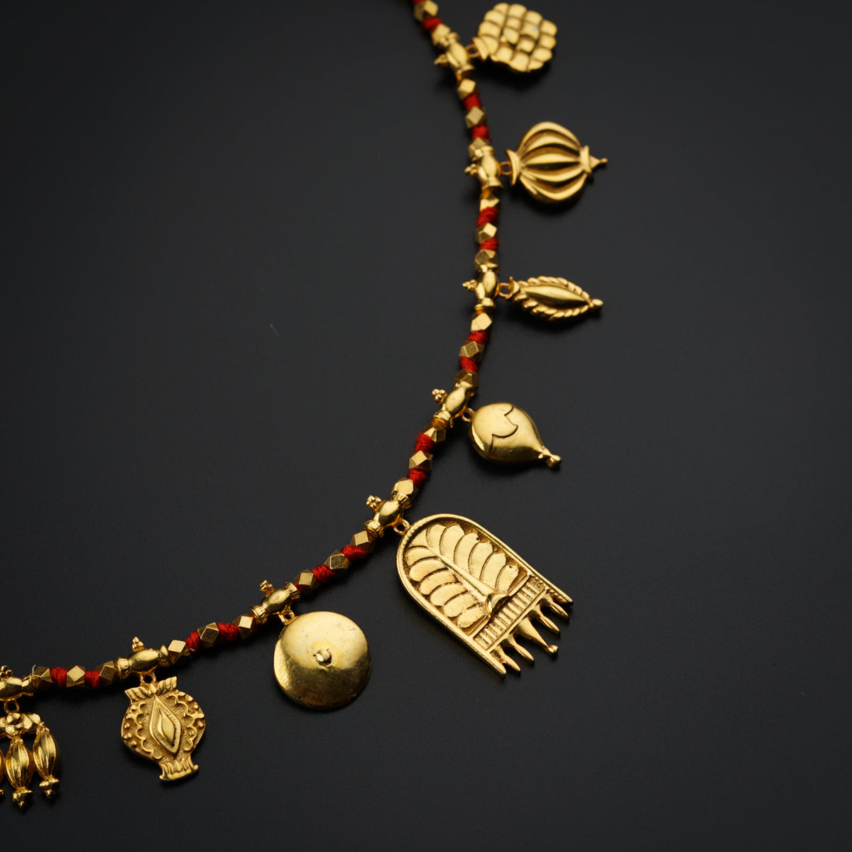 a gold necklace with red beads and charms