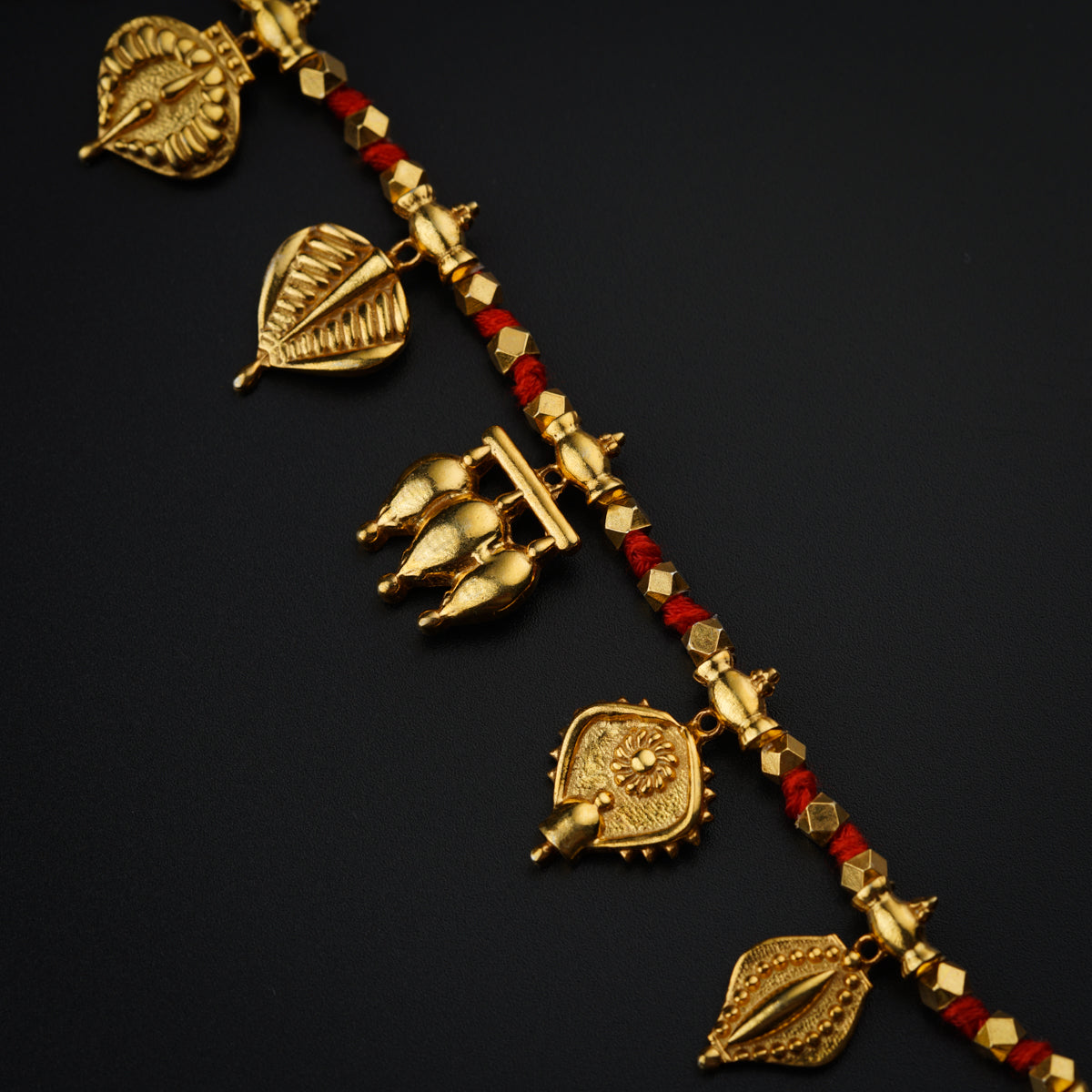 a gold necklace with red and white beads