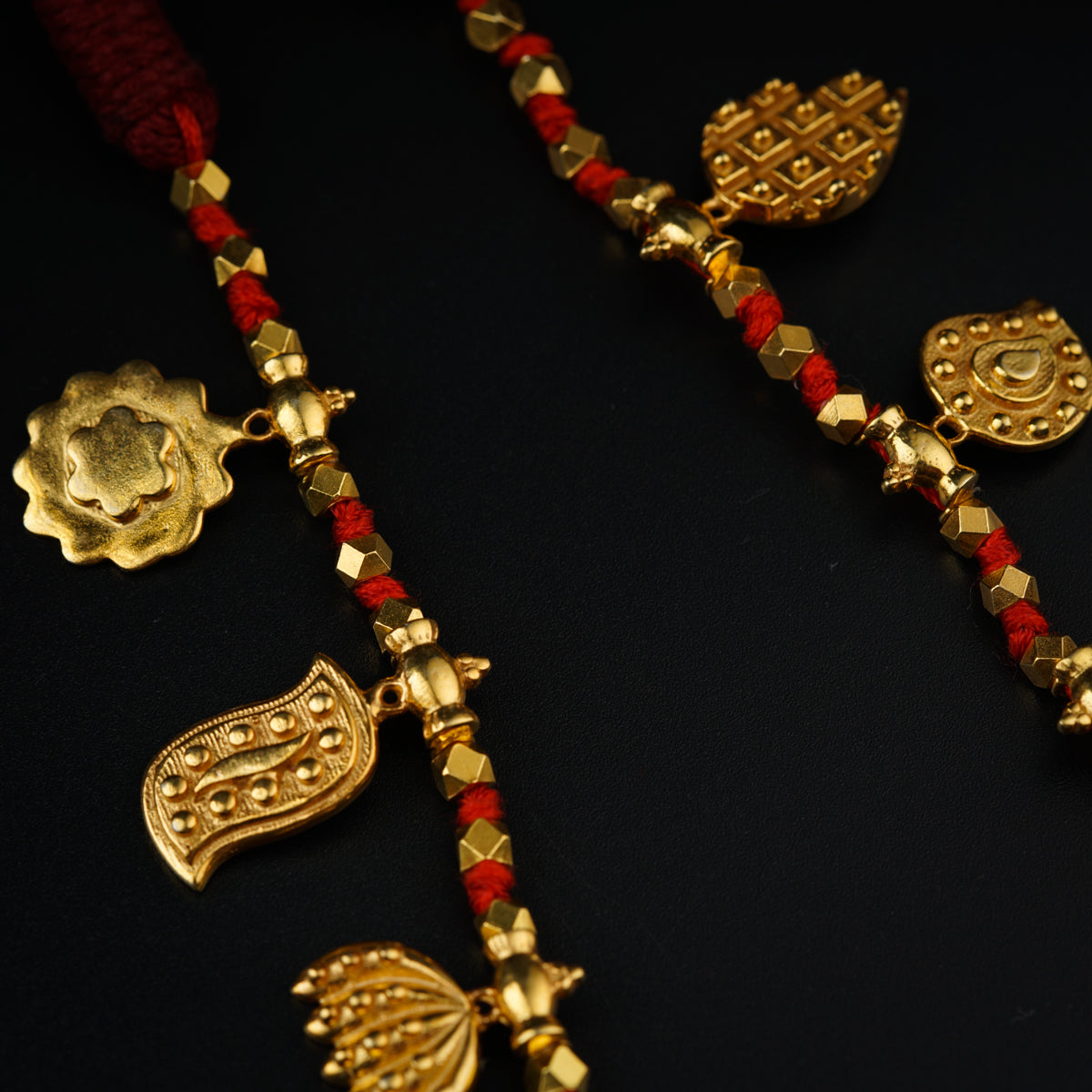 a close up of a gold necklace with red beads