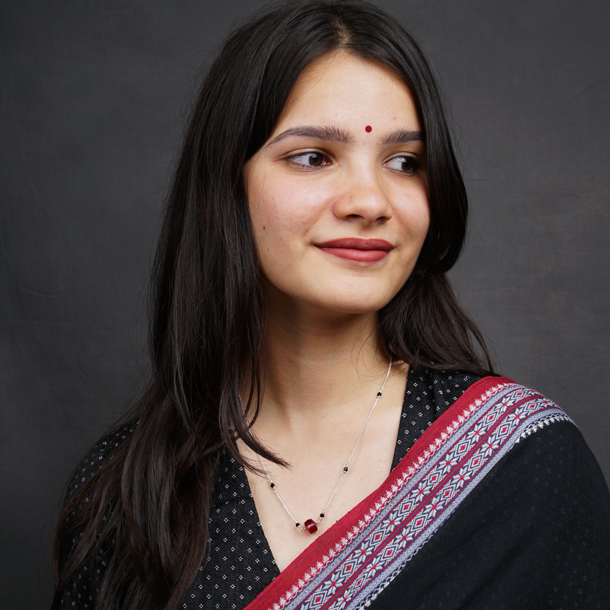 a woman in a black and red sari poses for a picture