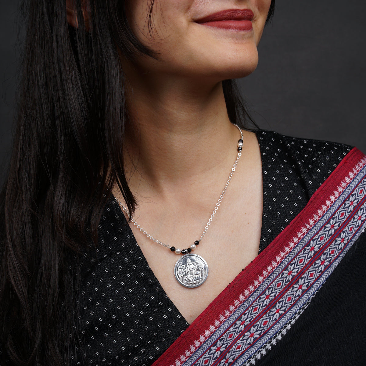 a woman wearing a necklace with a medallion on it
