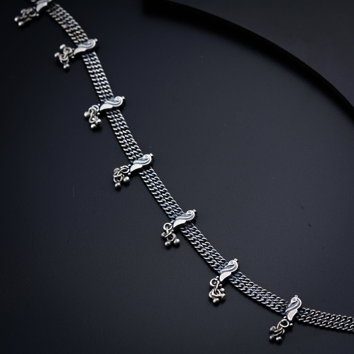 a silver chain bracelet on a black surface