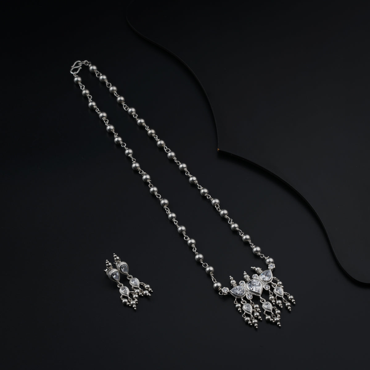 a necklace and earring set on a black surface