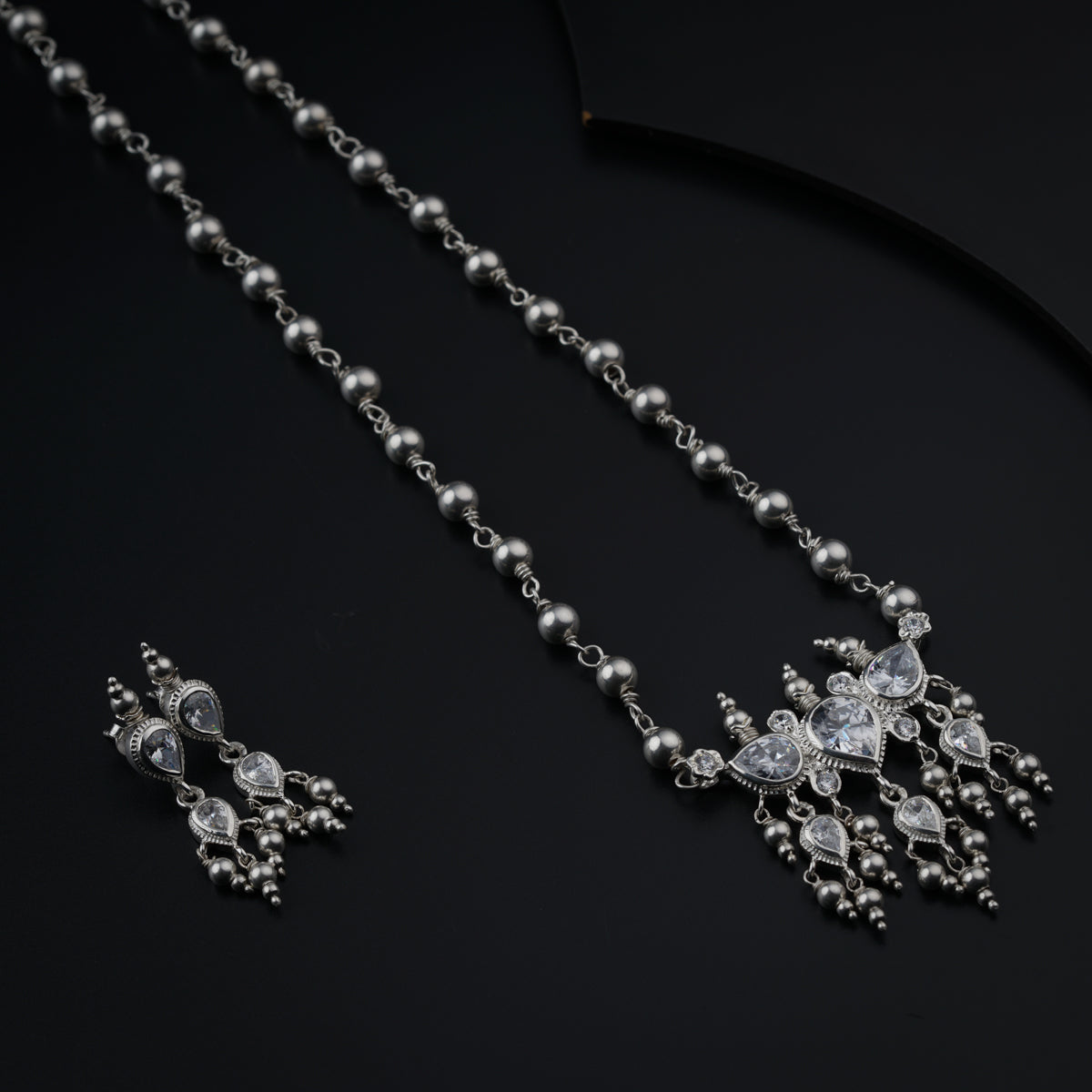 a necklace and earring set on a black surface