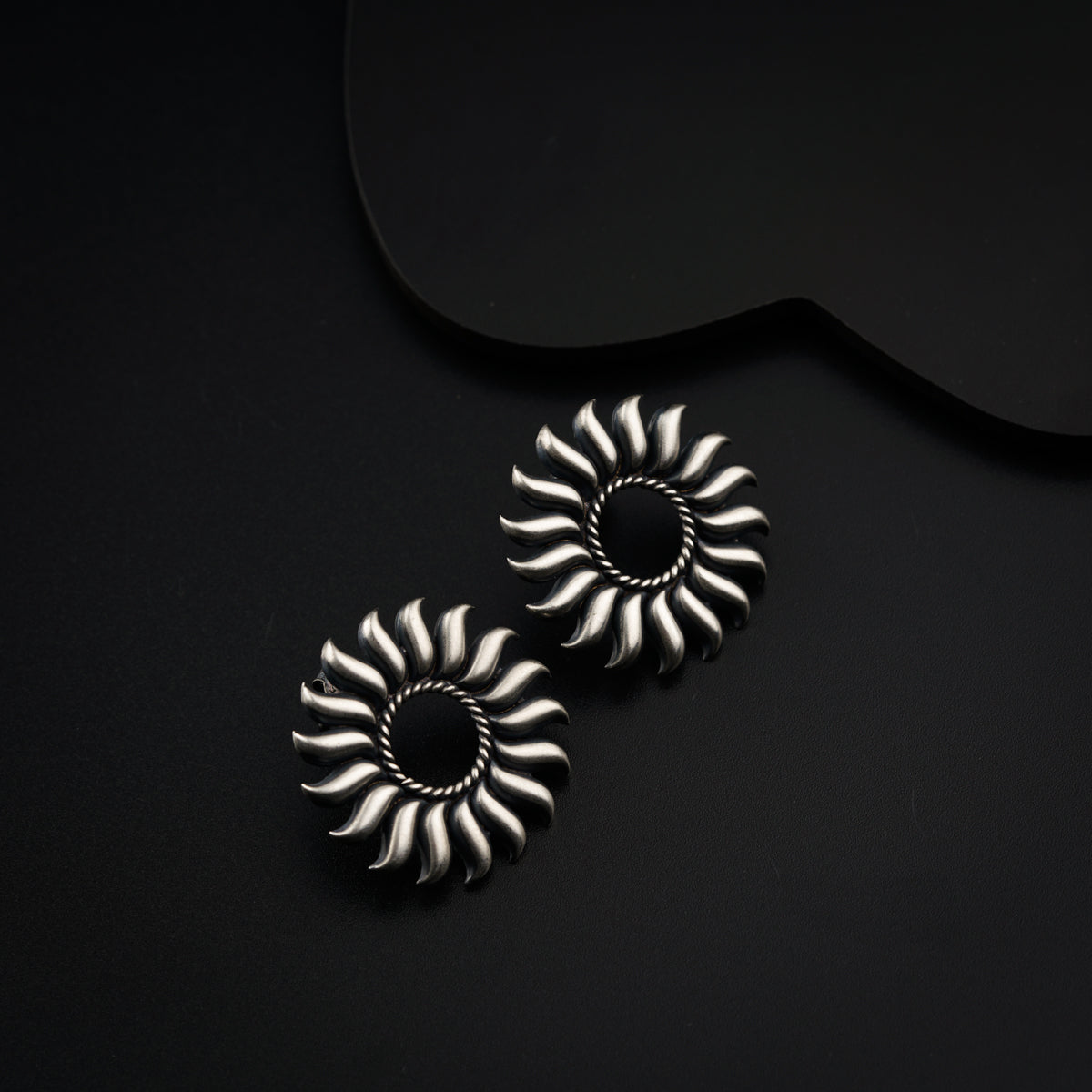 a pair of earrings sitting on top of a black surface