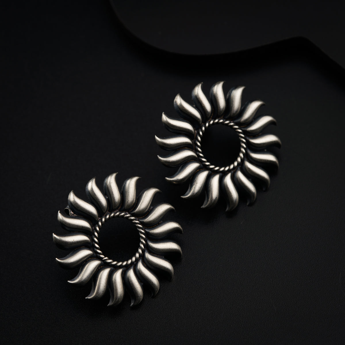 a pair of silver earrings sitting on top of a black surface