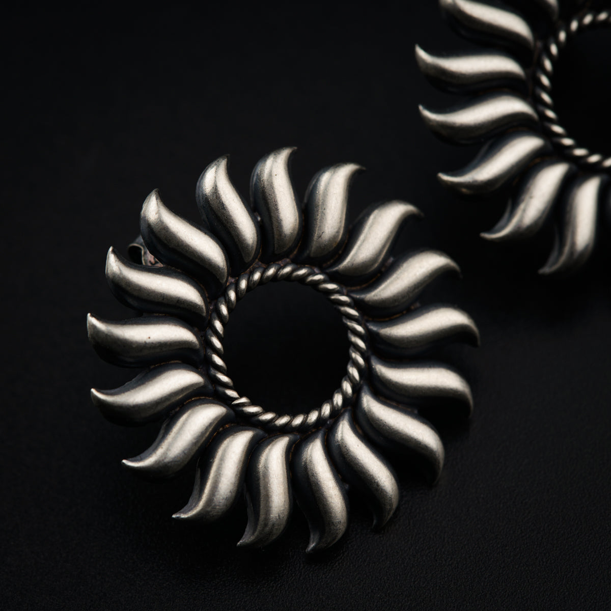 a pair of silver earrings sitting on top of a black surface