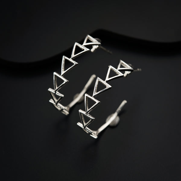 a pair of silver earrings sitting on top of a black surface