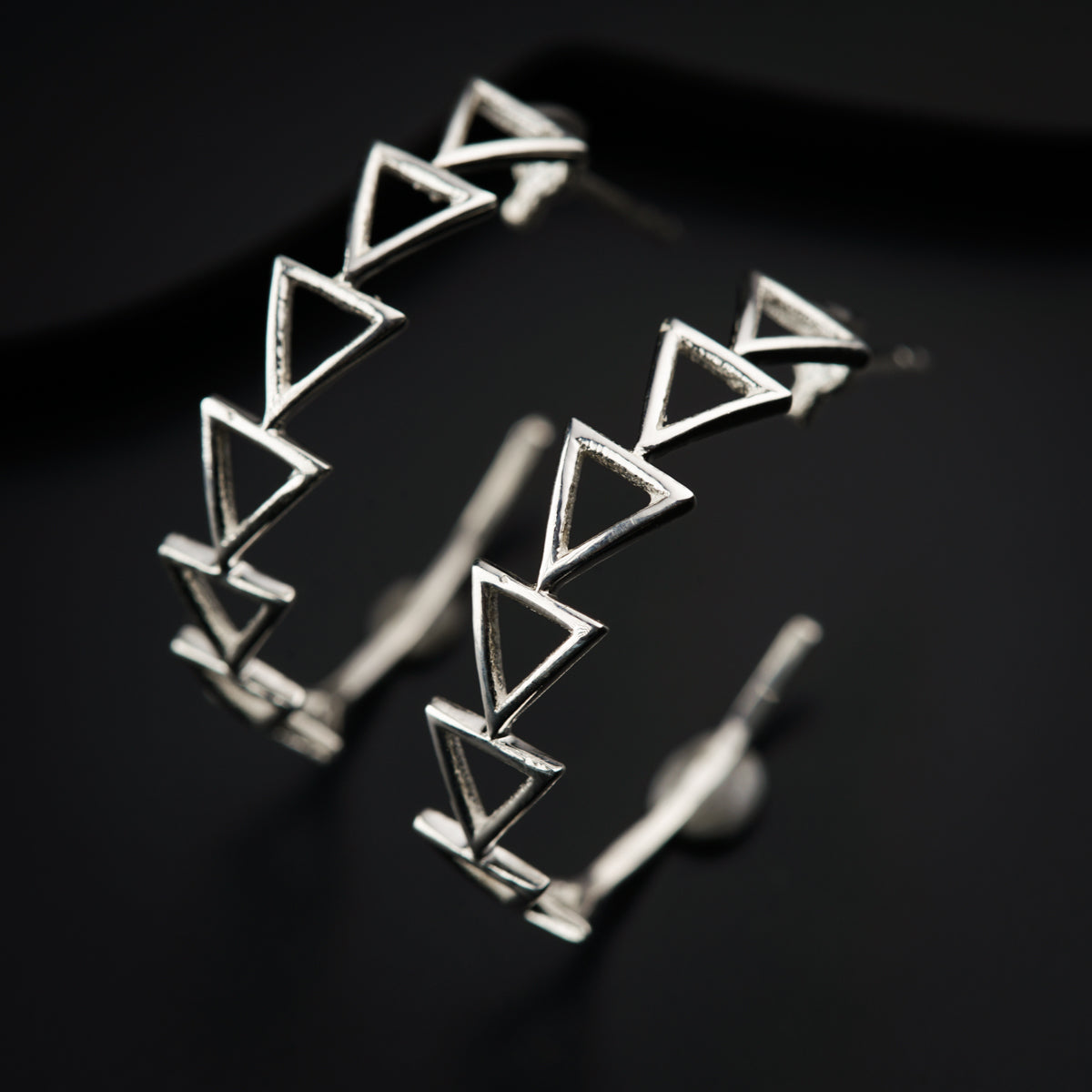 a pair of silver earrings on a black surface