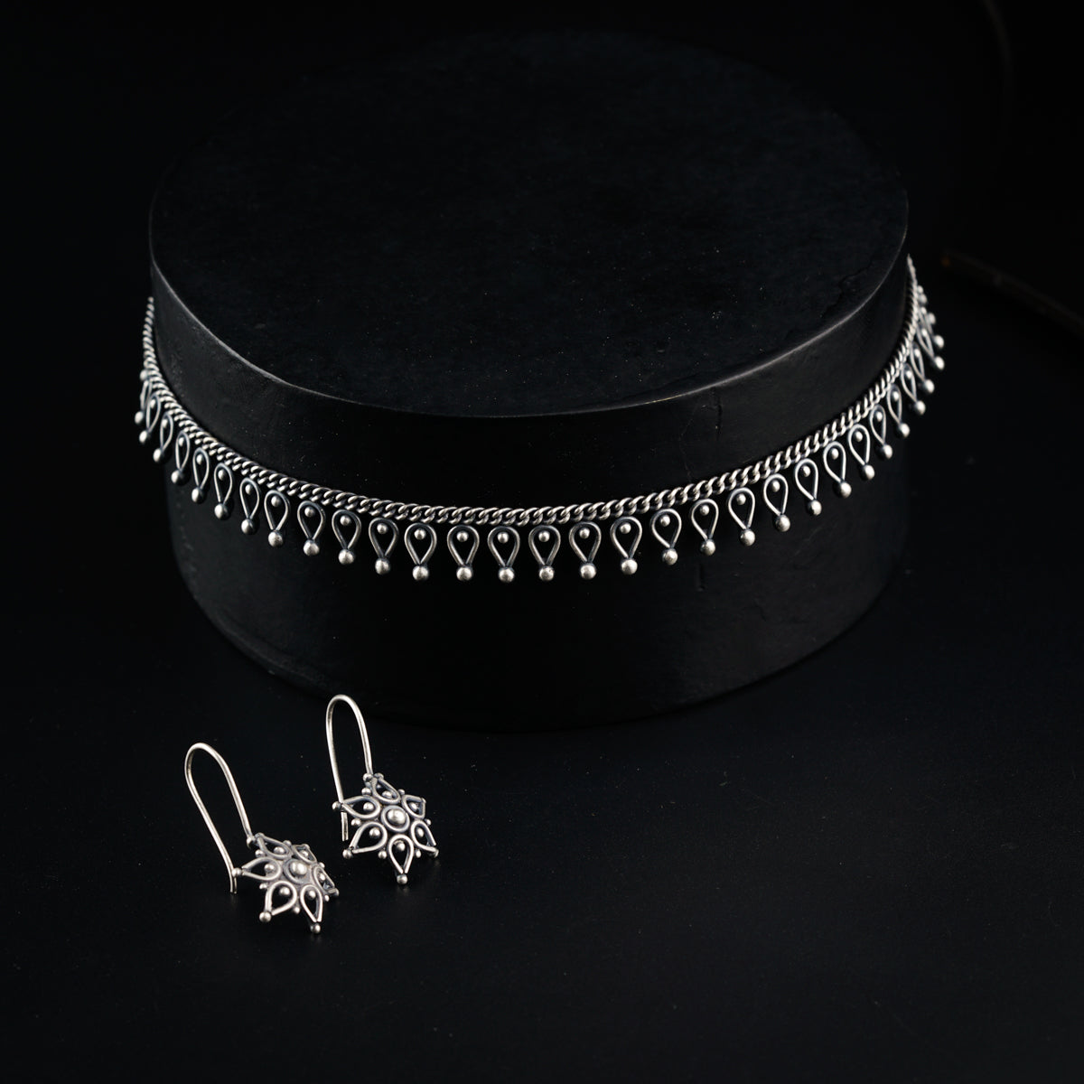 a pair of earrings sitting on top of a black box