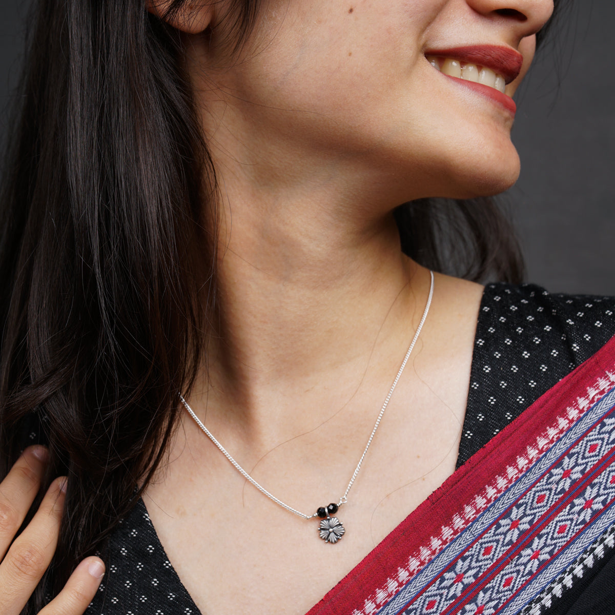 a woman wearing a necklace with a flower on it
