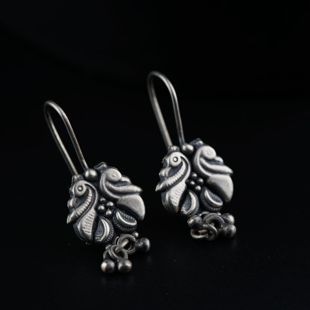 a pair of silver earrings on a black background