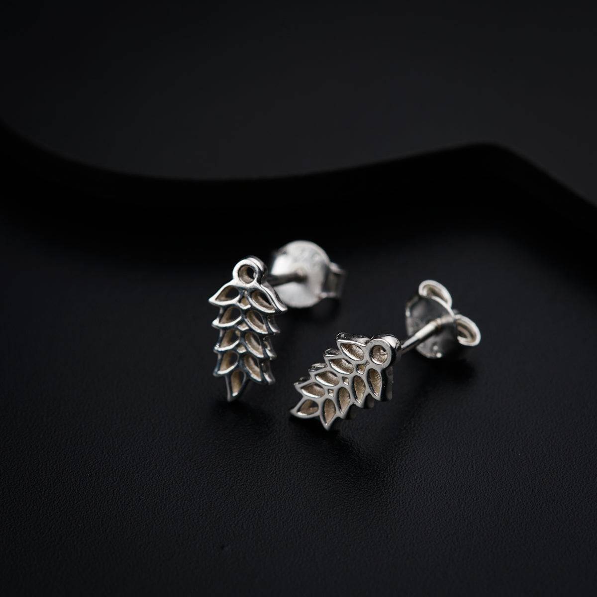 a pair of silver earrings on a black surface