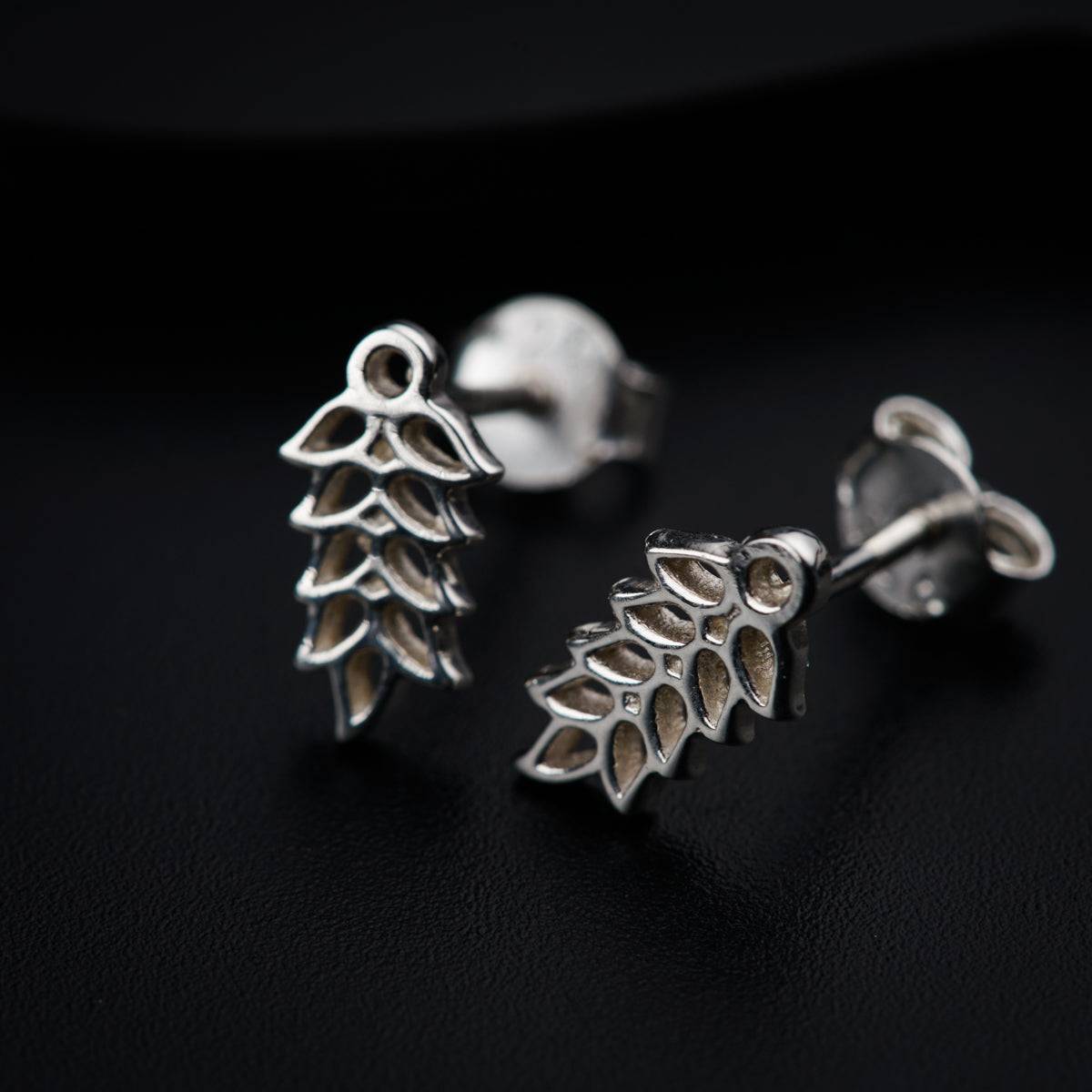a pair of earrings sitting on top of a black surface