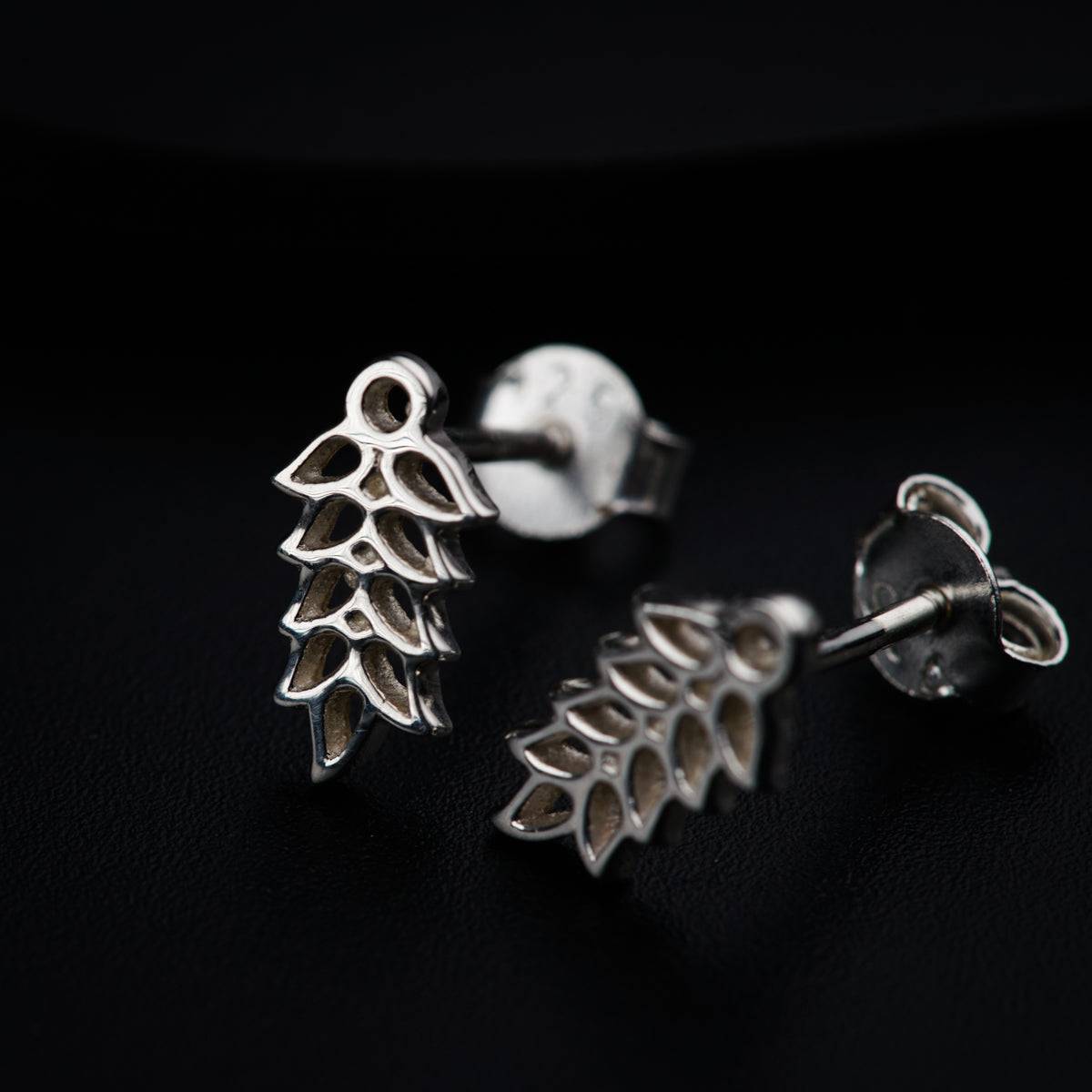 a pair of earrings sitting on top of a black surface