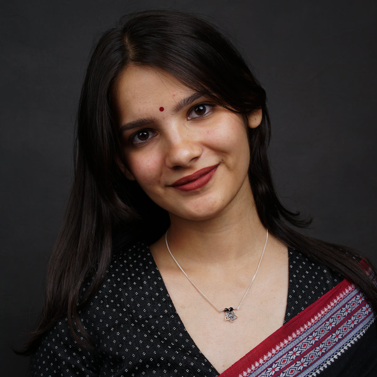 a woman wearing a necklace and a black shirt