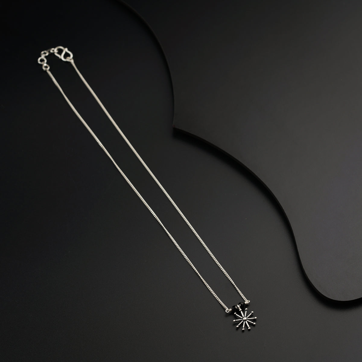 a black and white photo of a necklace on a black background