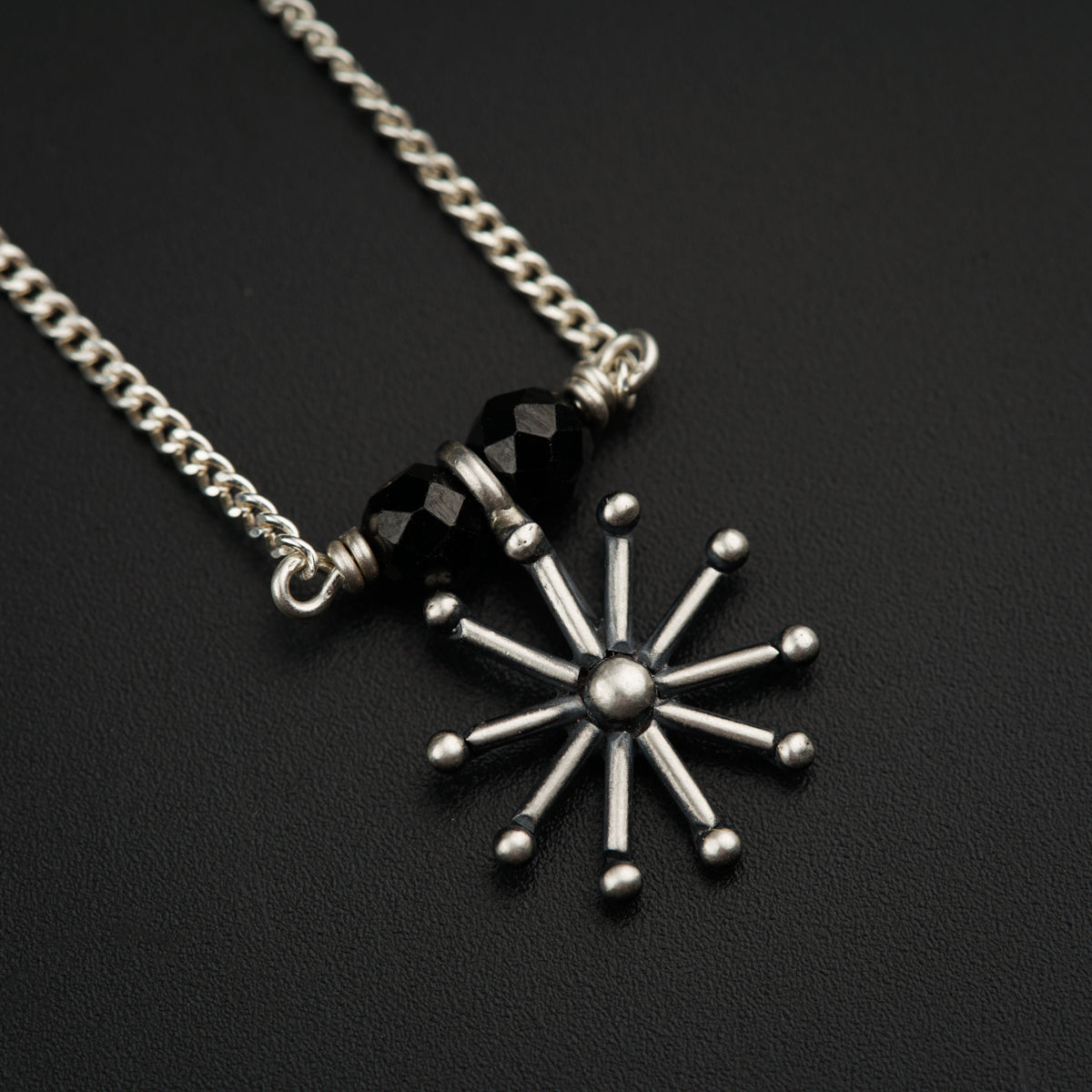 a black and white snowflake necklace on a black surface
