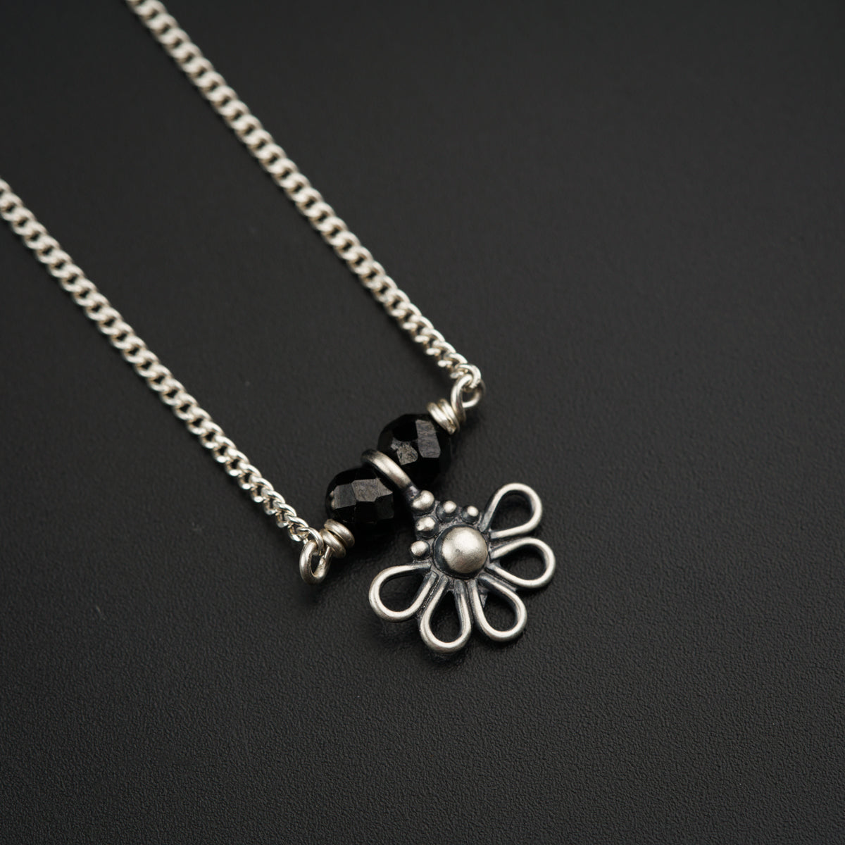 a necklace with a flower and a bead hanging from it