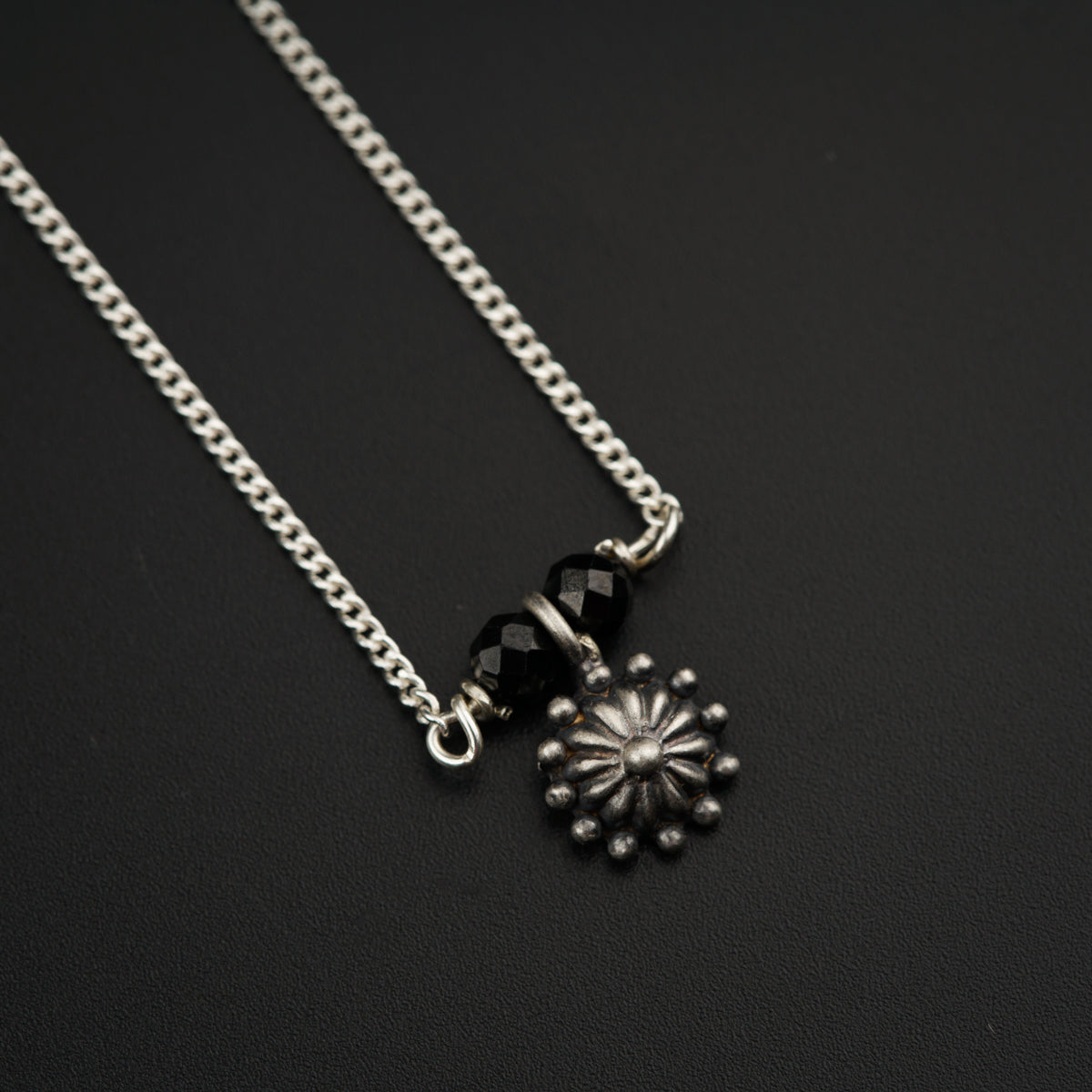 a black and silver necklace with a flower on it
