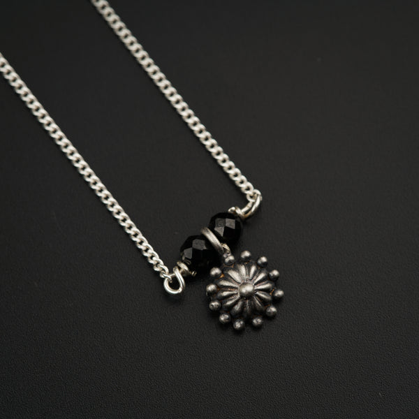 a black and silver necklace with a flower on it