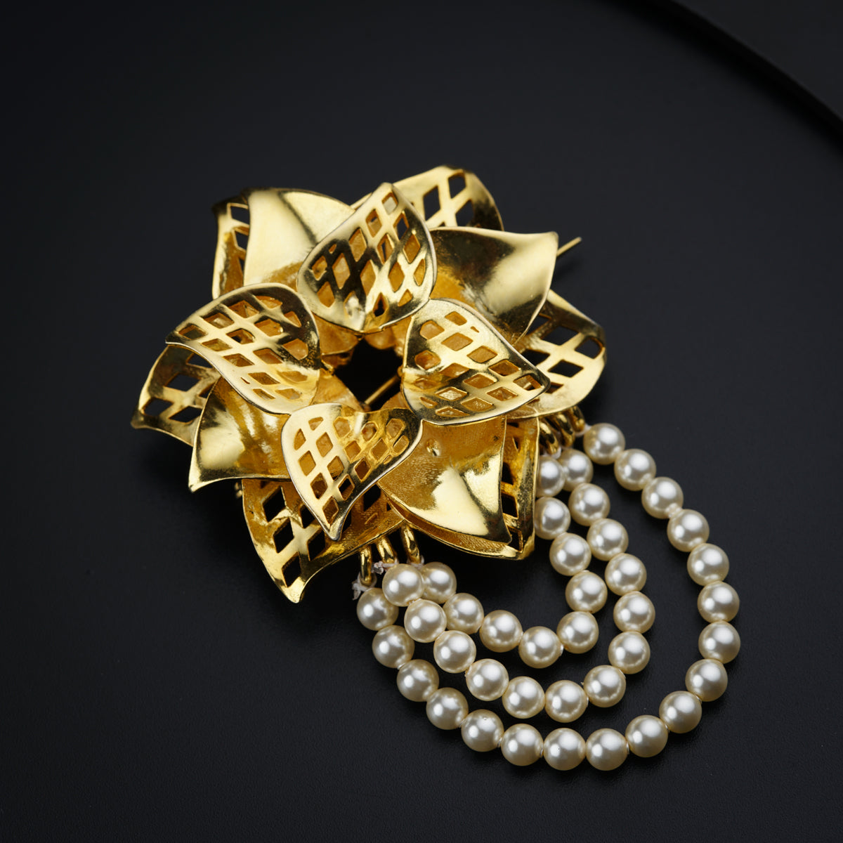 a golden brooch with pearls on a black surface