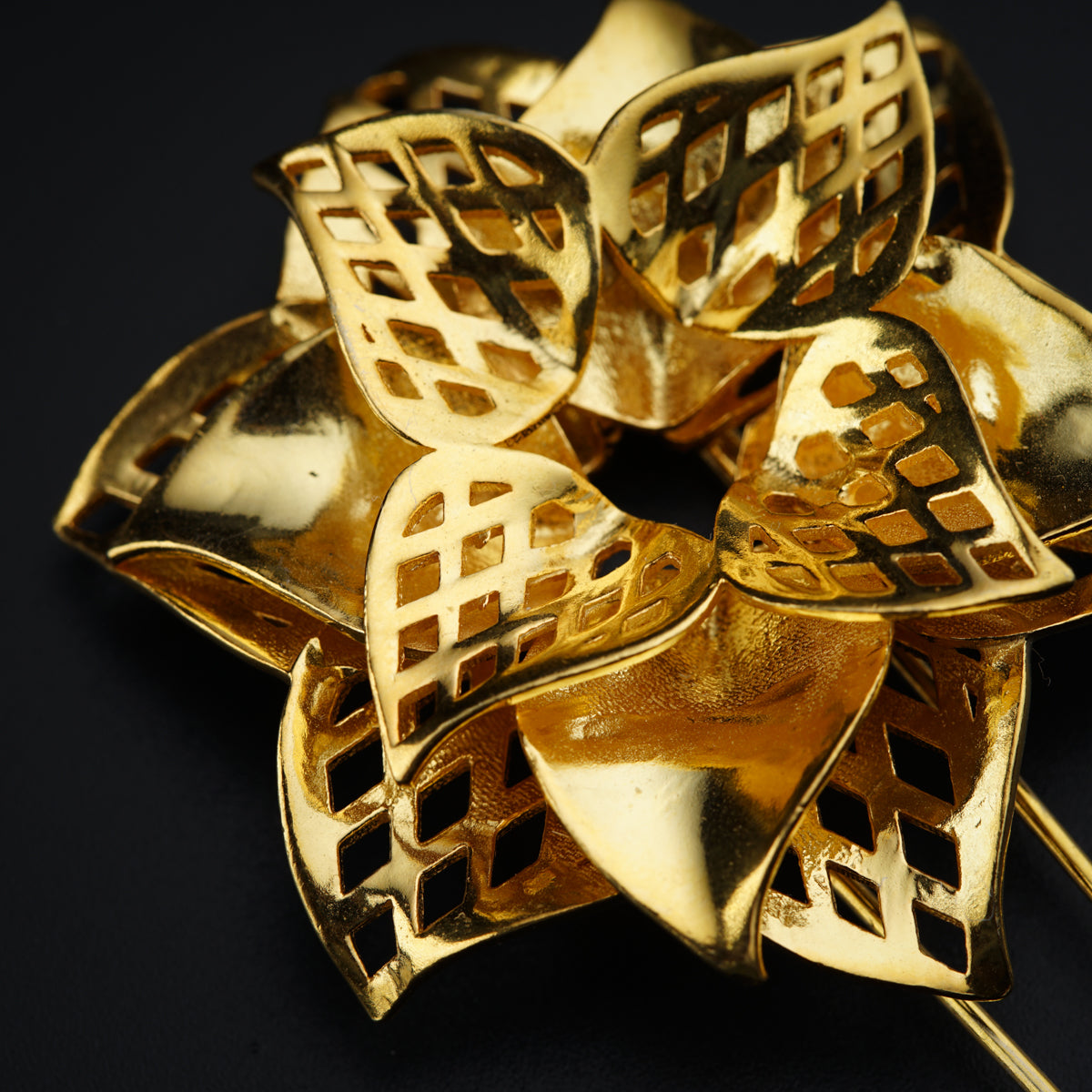 a close up of a gold brooch on a black background