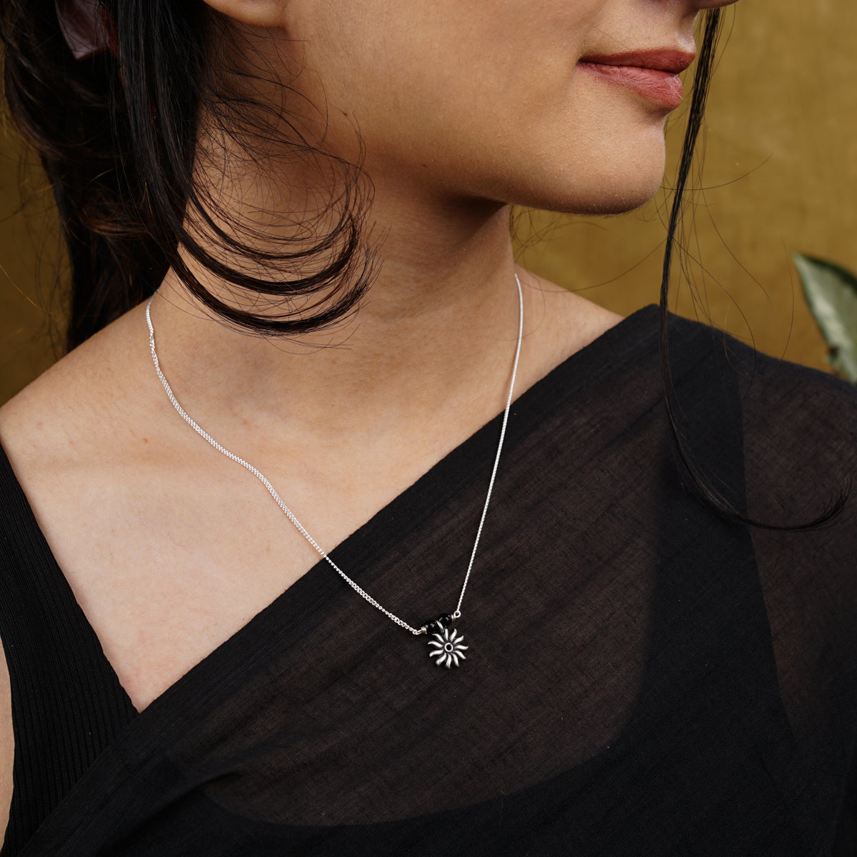 a woman wearing a necklace with a flower on it