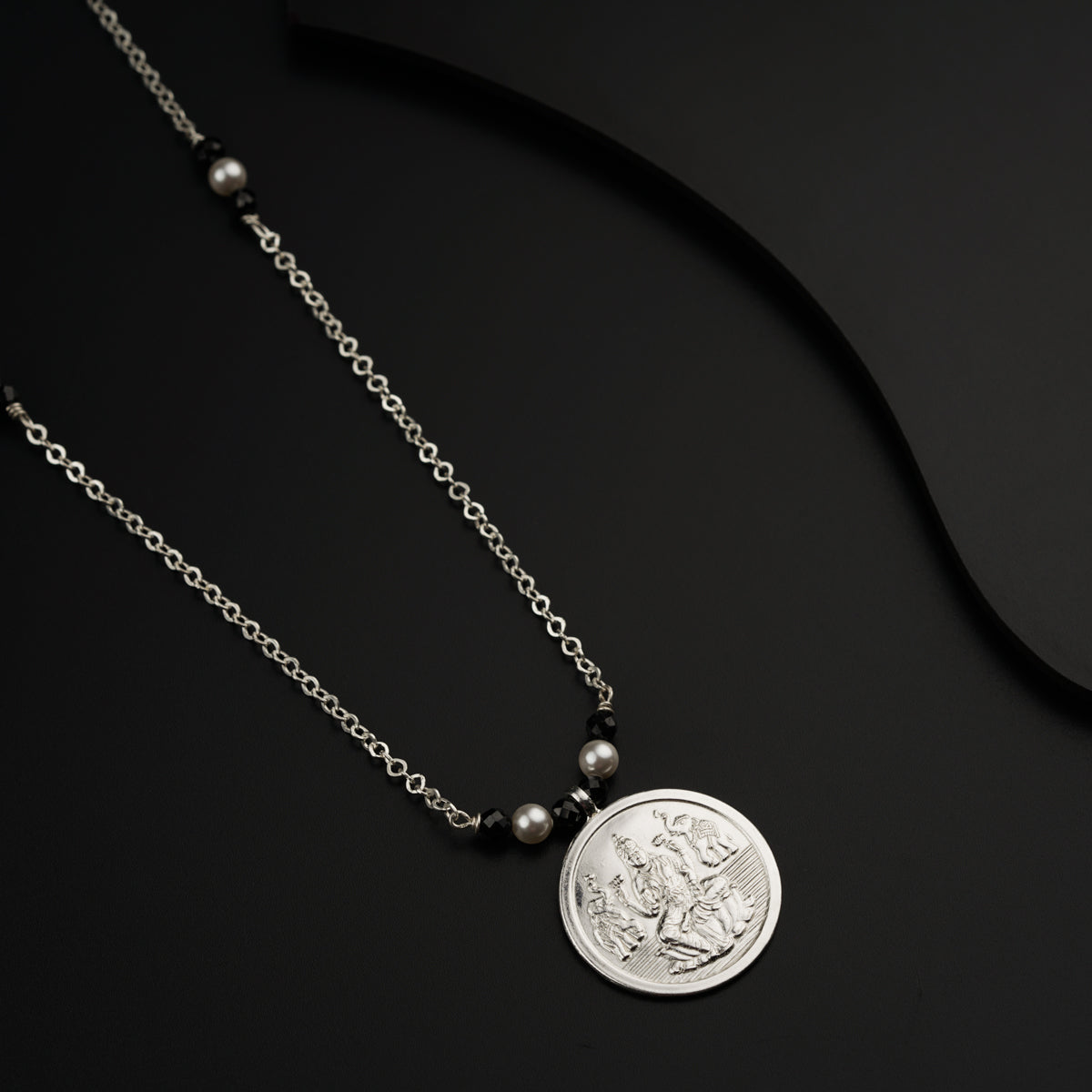 a necklace with a coin on a black background