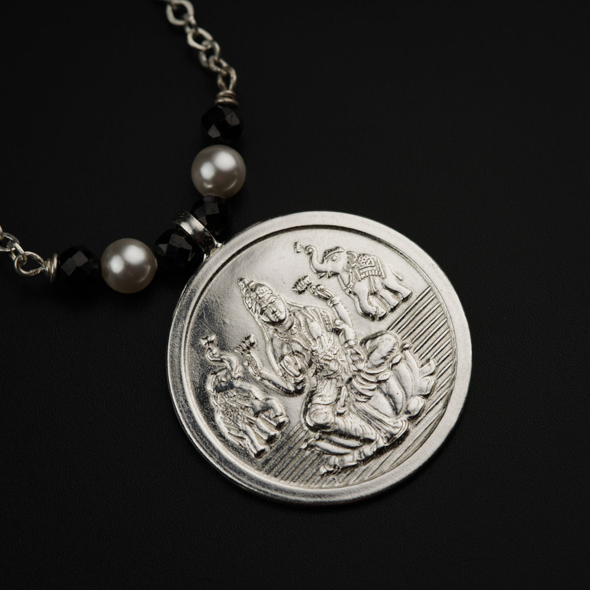a necklace with a coin on a black background