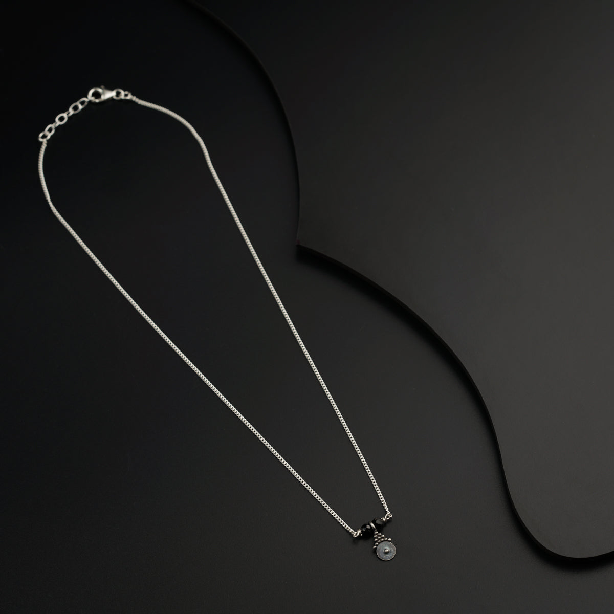 a black and white photo of a necklace on a black background