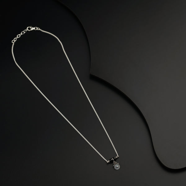 a black and white photo of a necklace on a black background