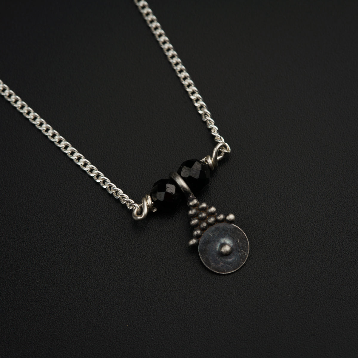 a black and silver necklace on a black surface