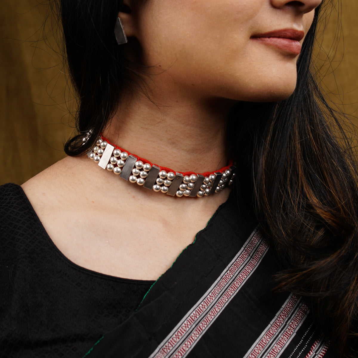 a woman wearing a red and silver necklace