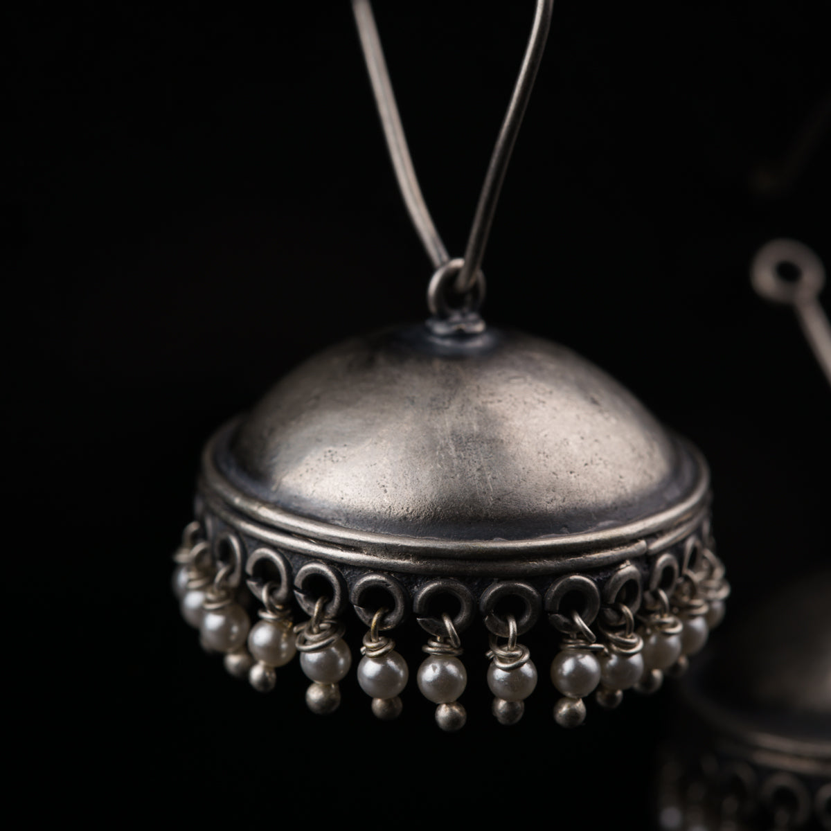 a silver bell with pearls hanging from it