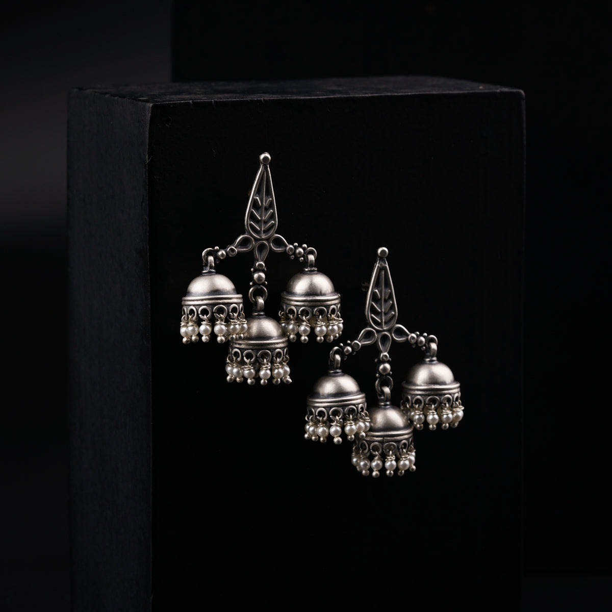 a pair of silver bells hanging from a black box