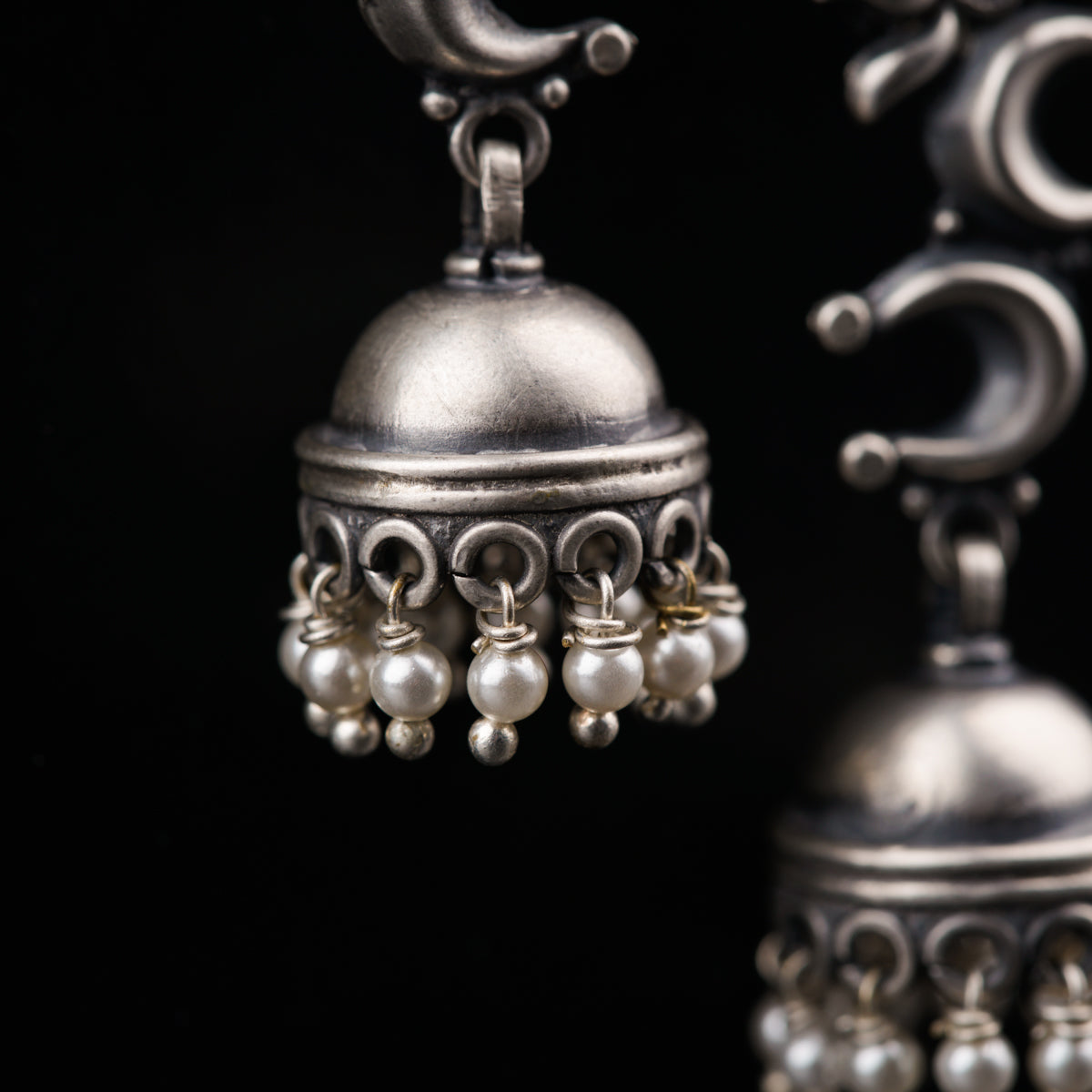 a pair of silver bells with pearls hanging from them
